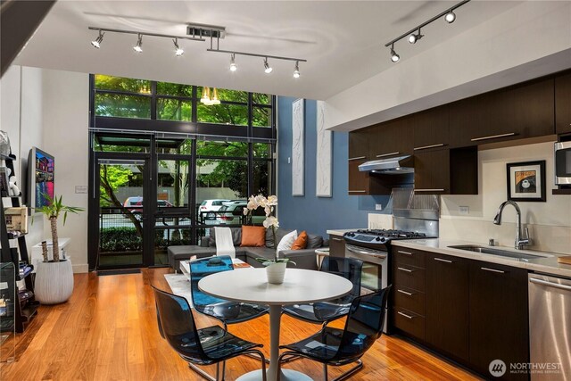 2911 2nd Ave Unit 120, Seattle, WA 98121 - kitchen featuring range hood, stainless steel appliances, rail lighting, and modern cabinets