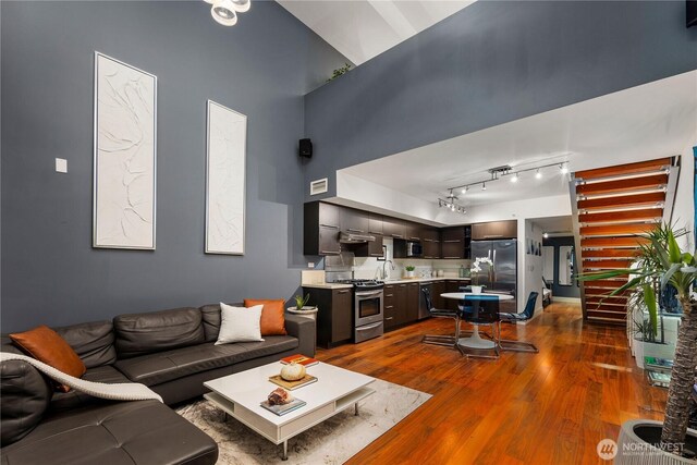 2911 2nd Ave Unit 120, Seattle, WA 98121 - living area with dark wood-style flooring, a towering ceiling, and track lighting