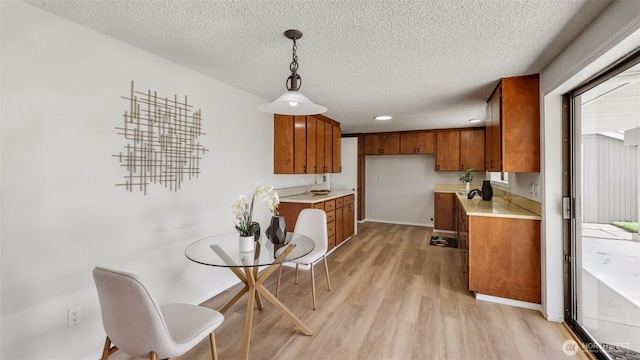 1517 126th Ave E, Edgewood, WA 98372 - kitchen with brown cabinets, light wood-style floors, light countertops, a textured ceiling, and decorative light fixtures