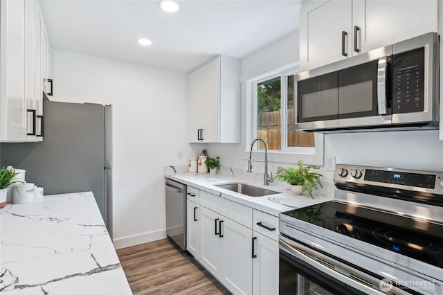 4130 Palatine Ave N, Seattle, WA 98103 - kitchen with appliances with stainless steel finishes, wood finished floors, white cabinets, light stone counters, and recessed lighting