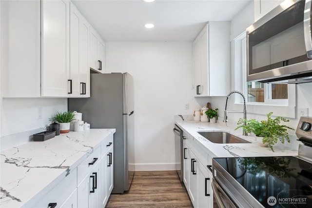 4130 Palatine Ave N, Seattle, WA 98103 - kitchen featuring appliances with stainless steel finishes, recessed lighting, wood finished floors, white cabinetry, and light stone counters