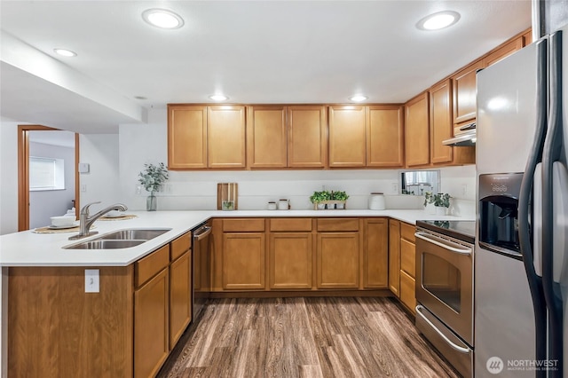 4130 Palatine Ave N, Seattle, WA 98103 - kitchen featuring stainless steel appliances, under cabinet range hood, wood finished floors, light countertops, and a peninsula