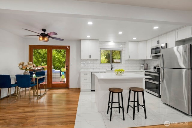 2536 S 286th St, Federal Way, WA 98003 - kitchen featuring stainless steel appliances, light countertops, backsplash, a breakfast bar, and recessed lighting