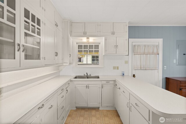 802 May St, Raymond, WA 98577 - kitchen featuring light countertops, white cabinetry, electric panel, glass insert cabinets, and a peninsula