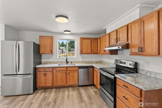110 Cedar Crest Pl, Napavine, WA 98532 - kitchen featuring appliances with stainless steel finishes, under cabinet range hood, light wood-style flooring, brown cabinetry, and a textured ceiling