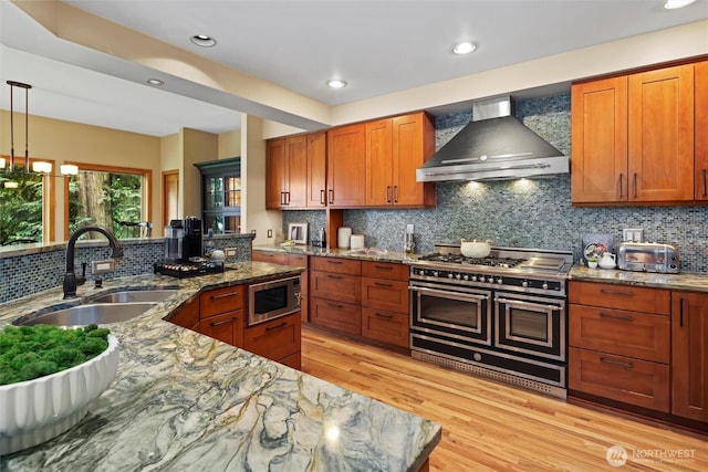 18608 SE 58th St, Issaquah, WA 98027 - kitchen featuring wall chimney range hood, stainless steel appliances, light wood-style flooring, tasteful backsplash, and recessed lighting