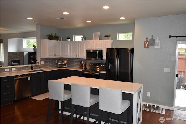 4201 Mckinley St NE, Lacey, WA 98516 - kitchen with black appliances, a breakfast bar, dark wood-style floors, light countertops, and recessed lighting