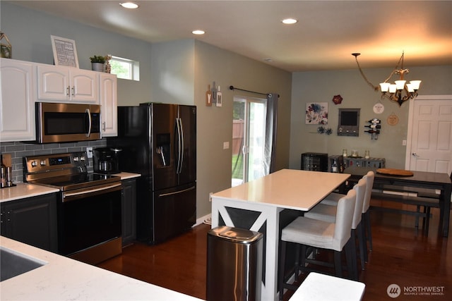 4201 Mckinley St NE, Lacey, WA 98516 - kitchen with appliances with stainless steel finishes, light countertops, dark wood-type flooring, a kitchen bar, and recessed lighting