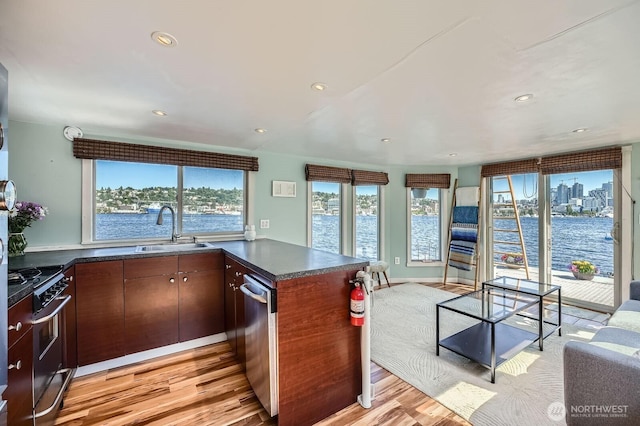 1818 Westlake Ave N Unit D-33, Seattle, WA 98109 - kitchen with stainless steel appliances, dark countertops, a peninsula, light wood finished floors, and recessed lighting