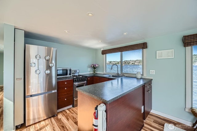 1818 Westlake Ave N Unit D-33, Seattle, WA 98109 - kitchen featuring stainless steel appliances, dark countertops, a peninsula, light wood-type flooring, and recessed lighting