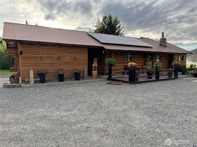 8 Iris Ln, Twisp, WA 98856 - view of front of property with log exterior, solar panels, a metal roof, and a porch