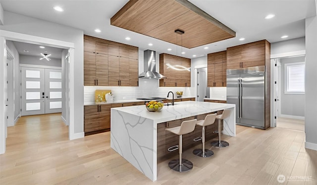 1542 213th Ct NE, Sammamish, WA 98074 - kitchen with wall chimney range hood, appliances with stainless steel finishes, brown cabinetry, modern cabinets, and backsplash