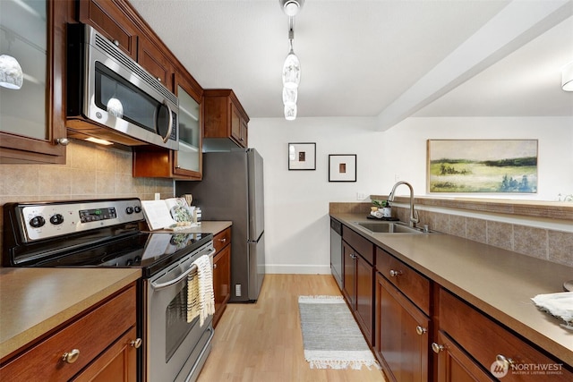 300 N 130th St Unit 2306, Seattle, WA 98133 - kitchen with stainless steel appliances, backsplash, glass insert cabinets, light wood finished floors, and pendant lighting