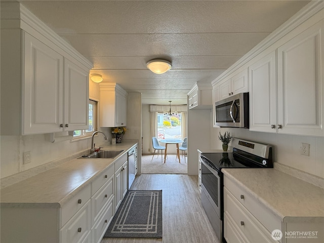 1200 Lincoln St Unit 418, Bellingham, WA 98229 - kitchen with appliances with stainless steel finishes, white cabinetry, a chandelier, and plenty of natural light