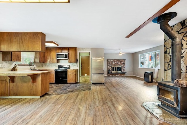 636 Nevil Rd, Winlock, WA 98596 - kitchen featuring a wood stove, stainless steel appliances, brown cabinetry, and light wood-style floors