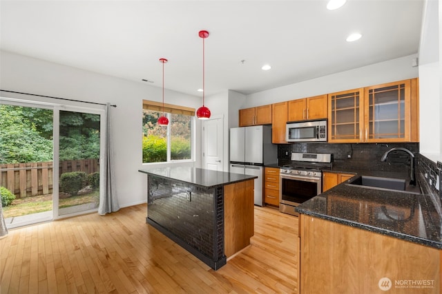 21270 40th Way S Unit 35, Seatac, WA 98198 - kitchen featuring appliances with stainless steel finishes, tasteful backsplash, light wood-style flooring, dark stone countertops, and brown cabinetry