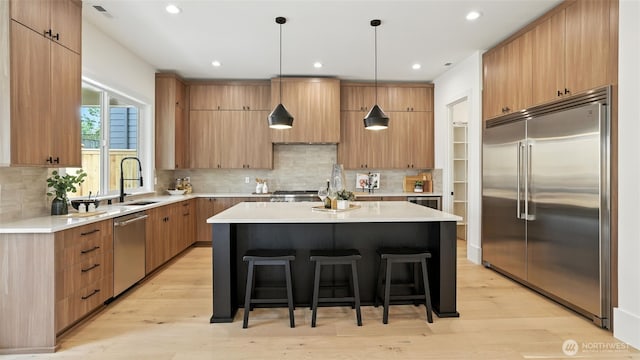 1118 N 34th St, Renton, WA 98056 - kitchen with stainless steel appliances, a breakfast bar, a center island, light wood-type flooring, and recessed lighting