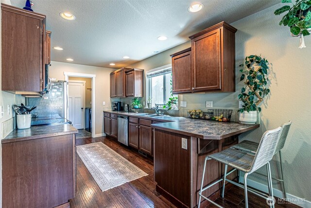 5003 Madison Heights Ct SE, Olympia, WA 98501 - kitchen featuring dark countertops, a peninsula, dishwasher, a kitchen breakfast bar, and recessed lighting