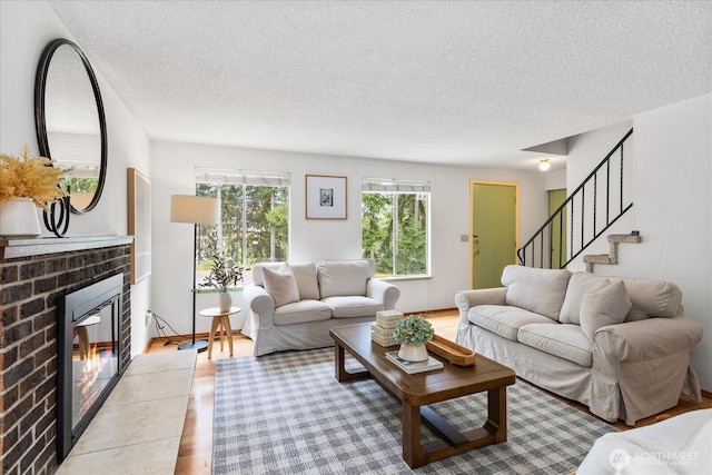 527 N 155th St, Shoreline, WA 98133 - living room featuring a textured ceiling, a brick fireplace, wood finished floors, and stairway