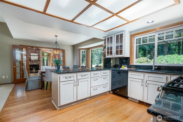 2327 31st Ave NW, Olympia, WA 98502 - kitchen with black dishwasher, a peninsula, light wood-style flooring, glass insert cabinets, and pendant lighting