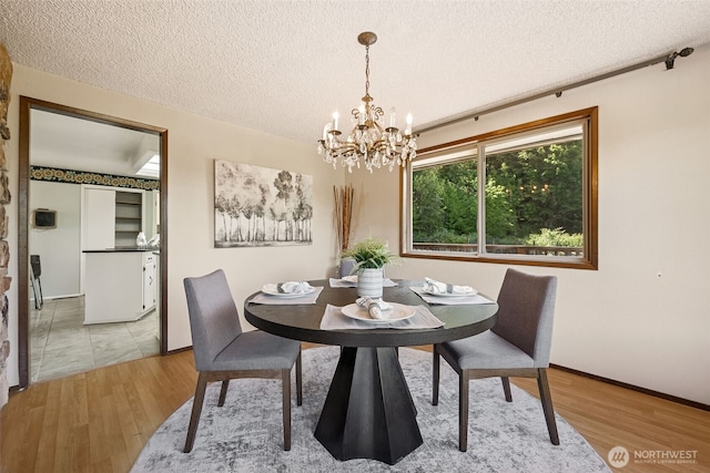 5415 Johnson Point Rd NE, Olympia, WA 98516 - dining room featuring a chandelier, wood finished floors, and a textured ceiling