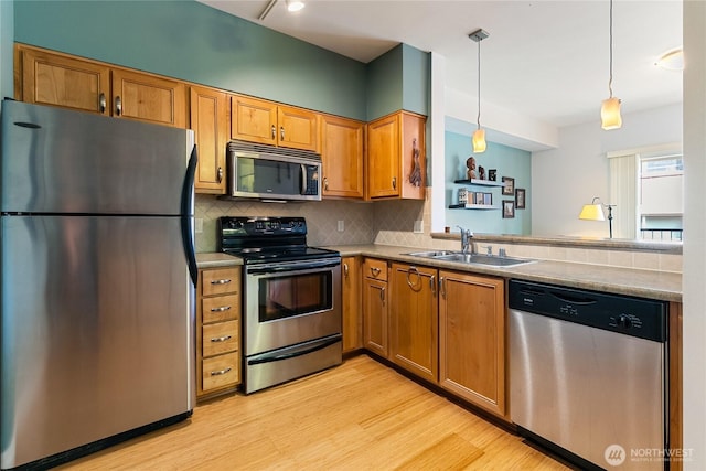 910 Harris Ave Unit 407, Bellingham, WA 98225 - kitchen featuring appliances with stainless steel finishes, light wood-style floors, decorative backsplash, brown cabinets, and pendant lighting