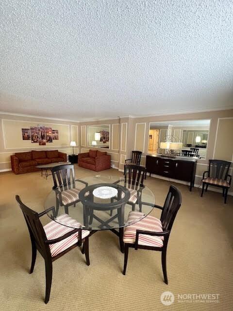 4540 8th Ave NE Unit 903, Seattle, WA 98105 - dining space featuring light carpet, a textured ceiling, and crown molding