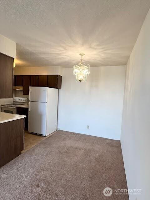 4540 8th Ave NE Unit 903, Seattle, WA 98105 - kitchen with white appliances, dark brown cabinets, light colored carpet, light countertops, and a chandelier