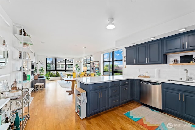 4116 California Ave SW Unit 309, Seattle, WA 98116 - kitchen with stainless steel dishwasher, open shelves, blue cabinets, and a peninsula