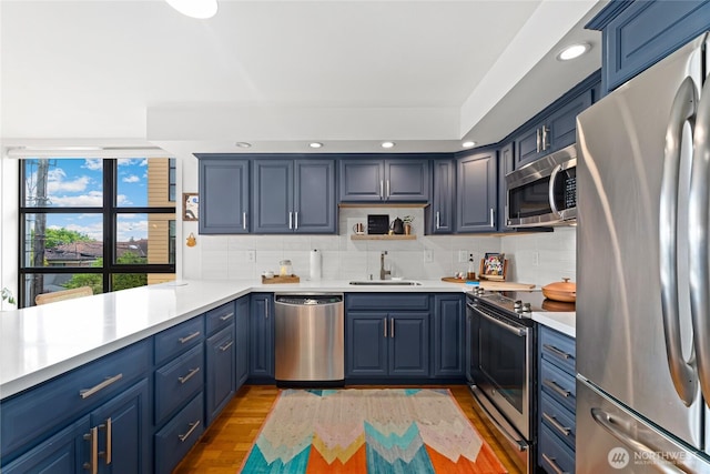4116 California Ave SW Unit 309, Seattle, WA 98116 - kitchen with stainless steel appliances, blue cabinets, light wood-style flooring, decorative backsplash, and recessed lighting