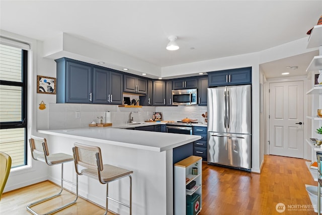 4116 California Ave SW Unit 309, Seattle, WA 98116 - kitchen featuring stainless steel appliances, open shelves, blue cabinetry, and a peninsula
