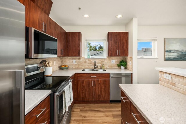 2101 N 55th St Unit 312, Seattle, WA 98103 - kitchen featuring stainless steel appliances, decorative backsplash, light countertops, light wood-style floors, and recessed lighting