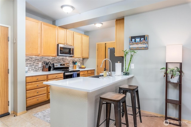 512 Darby Dr Unit 213, Bellingham, WA 98226 - kitchen with stainless steel appliances, a breakfast bar, a peninsula, light brown cabinets, and backsplash