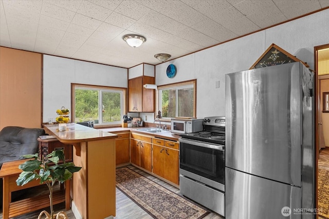 30710 223rd Ave NE, Arlington, WA 98223 - kitchen featuring stainless steel appliances, brown cabinets, light countertops, a peninsula, and light wood-type flooring