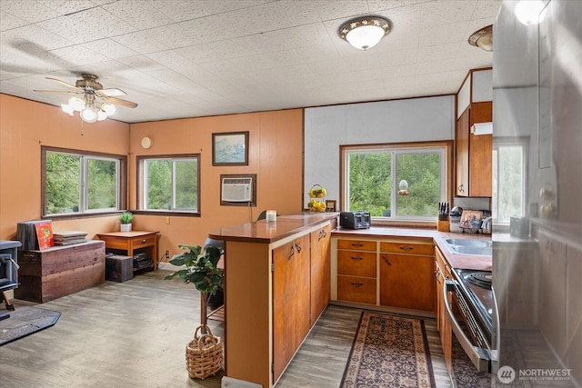 30710 223rd Ave NE, Arlington, WA 98223 - kitchen featuring stainless steel electric stove, a peninsula, wood finished floors, brown cabinets, and a wall mounted air conditioner
