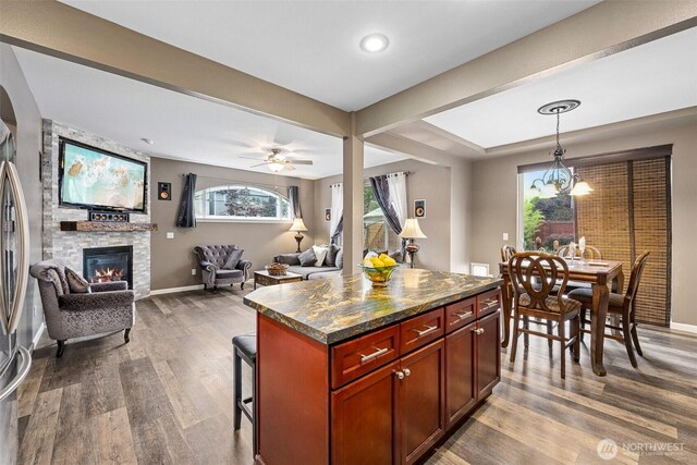 7726 162nd St E, Puyallup, WA 98375 - kitchen with dark wood-style flooring, a stone fireplace, open floor plan, a kitchen breakfast bar, and pendant lighting
