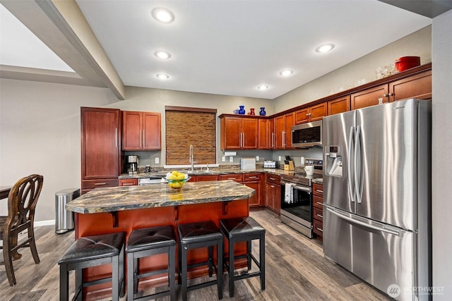 7726 162nd St E, Puyallup, WA 98375 - kitchen with stainless steel appliances, recessed lighting, a breakfast bar area, a center island, and dark wood-type flooring