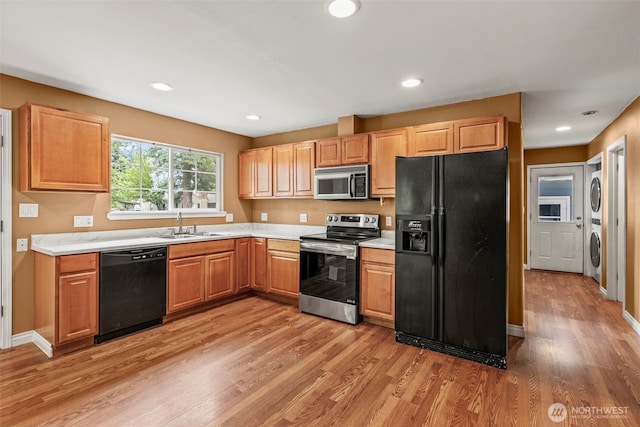 2132 Washington Way, Longview, WA 98632 - kitchen featuring black appliances, stacked washer and clothes dryer, light wood-type flooring, light countertops, and recessed lighting