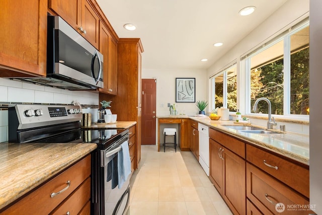 132 NE 130th St, Seattle, WA 98125 - kitchen featuring appliances with stainless steel finishes, brown cabinetry, light stone counters, light tile patterned floors, and tasteful backsplash