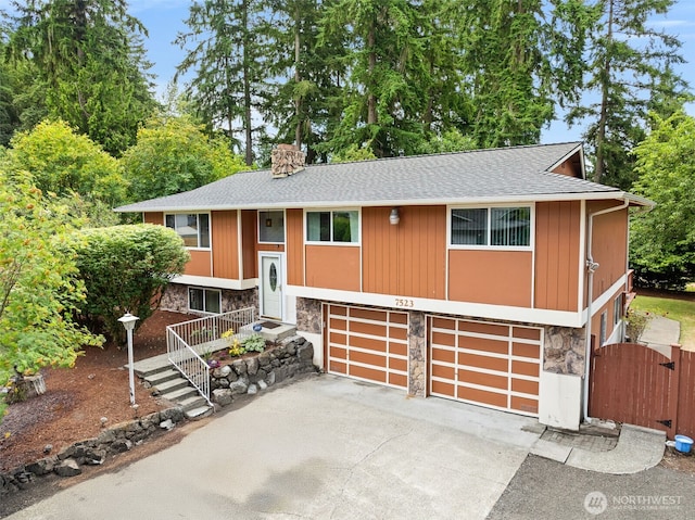 7523 13th Ave SE, Lacey, WA 98503 - bi-level home featuring stone siding, driveway, roof with shingles, an attached garage, and a chimney
