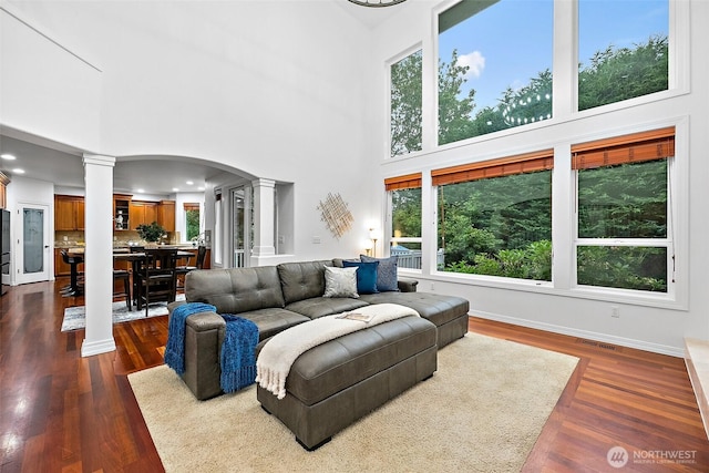 1402 180th Ave E, Lake Tapps, WA 98391 - living room featuring decorative columns, a towering ceiling, plenty of natural light, recessed lighting, and dark wood-style flooring