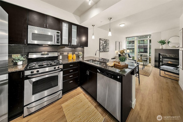 819 Virginia St Unit 1606, Seattle, WA 98101 - kitchen with stainless steel appliances, a peninsula, dark stone counters, light wood-type flooring, and pendant lighting