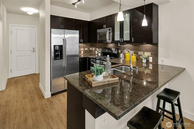 819 Virginia St Unit 1606, Seattle, WA 98101 - kitchen with stainless steel appliances, a peninsula, dark stone countertops, light wood finished floors, and a kitchen breakfast bar