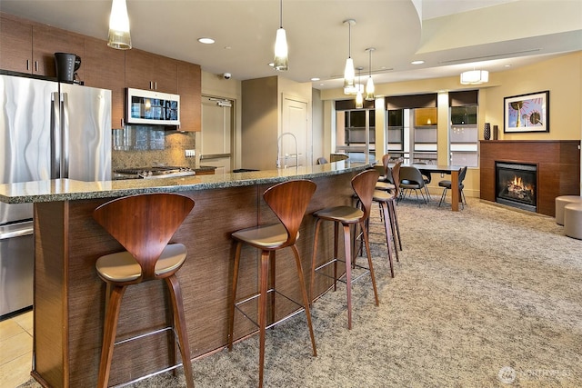 819 Virginia St Unit 1606, Seattle, WA 98101 - kitchen with white microwave, a kitchen bar, freestanding refrigerator, backsplash, and light carpet