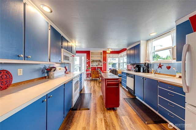 231 E 1st St, Port Angeles, WA 98362 - kitchen featuring blue cabinetry, white appliances, light countertops, wood finished floors, and a kitchen island
