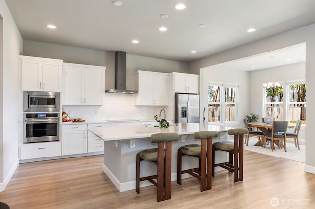 4490 Albatross St, Port Townsend, WA 98368 - kitchen with stainless steel appliances, wall chimney range hood, an island with sink, light countertops, and decorative backsplash