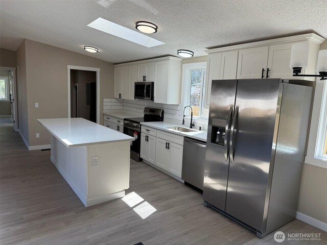 8102 195th St E Unit 95, Spanaway, WA 98387 - kitchen featuring appliances with stainless steel finishes, a skylight, backsplash, plenty of natural light, and vaulted ceiling