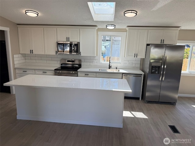 8102 195th St E Unit 95, Spanaway, WA 98387 - kitchen with appliances with stainless steel finishes, a skylight, backsplash, light wood-style floors, and light countertops