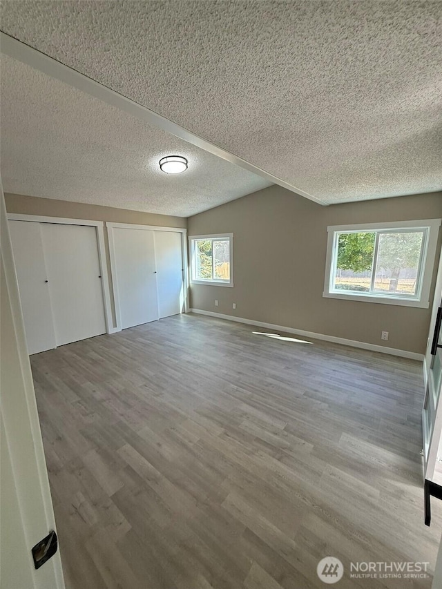 8102 195th St E Unit 95, Spanaway, WA 98387 - unfurnished bedroom featuring two closets, a textured ceiling, and wood finished floors