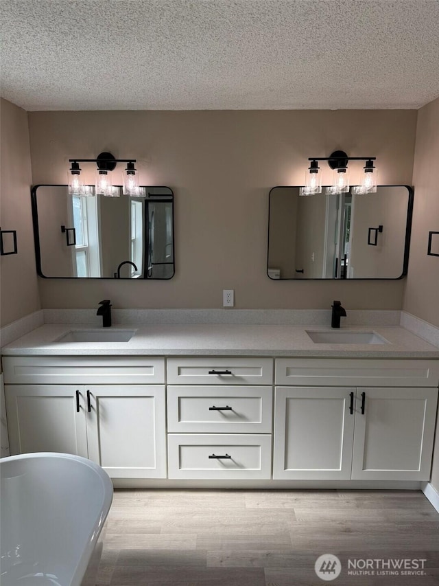 8102 195th St E Unit 95, Spanaway, WA 98387 - bathroom with a textured ceiling, double vanity, wood finished floors, and a freestanding bath